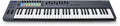 Black MIDI keyboard controller with 61 keys, multicolor pads, knobs, faders, and buttons on top.