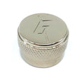 Close-up of a chrome metal knob with a textured grip and engraved logo on top.