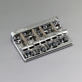 Silver metal bass bridge with four saddles and adjustment screws on a gray background.