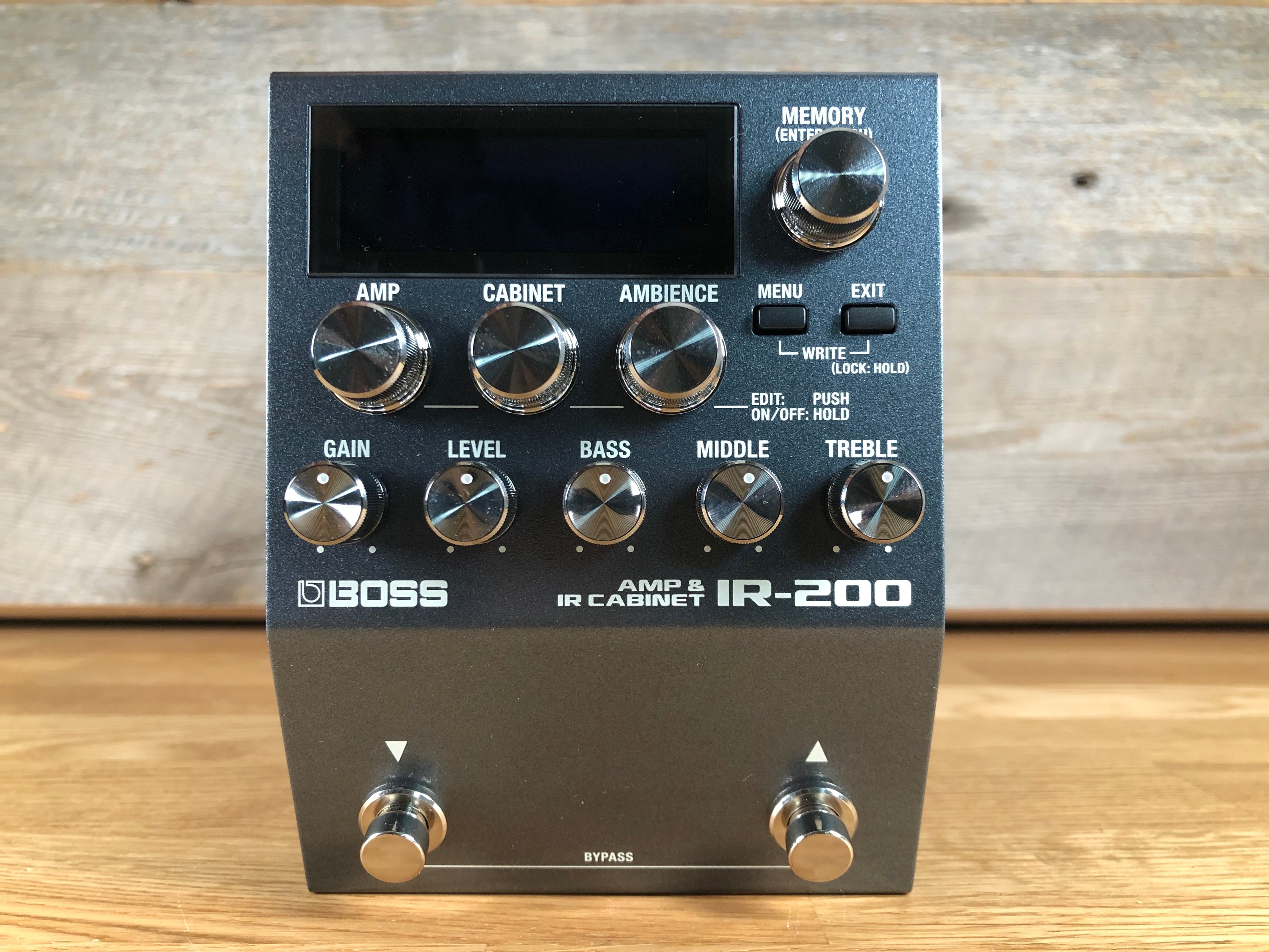 Black Boss IR-200 guitar effects pedal with multiple knobs, buttons, and two footswitches on wood surface.