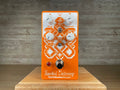 Orange guitar effects pedal with four knobs, toggle switch, footswitch, and red indicator light on front face.