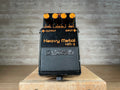 Black guitar effects pedal with orange knobs labeled Heavy Metal HM-2 by Boss shown from front top view.