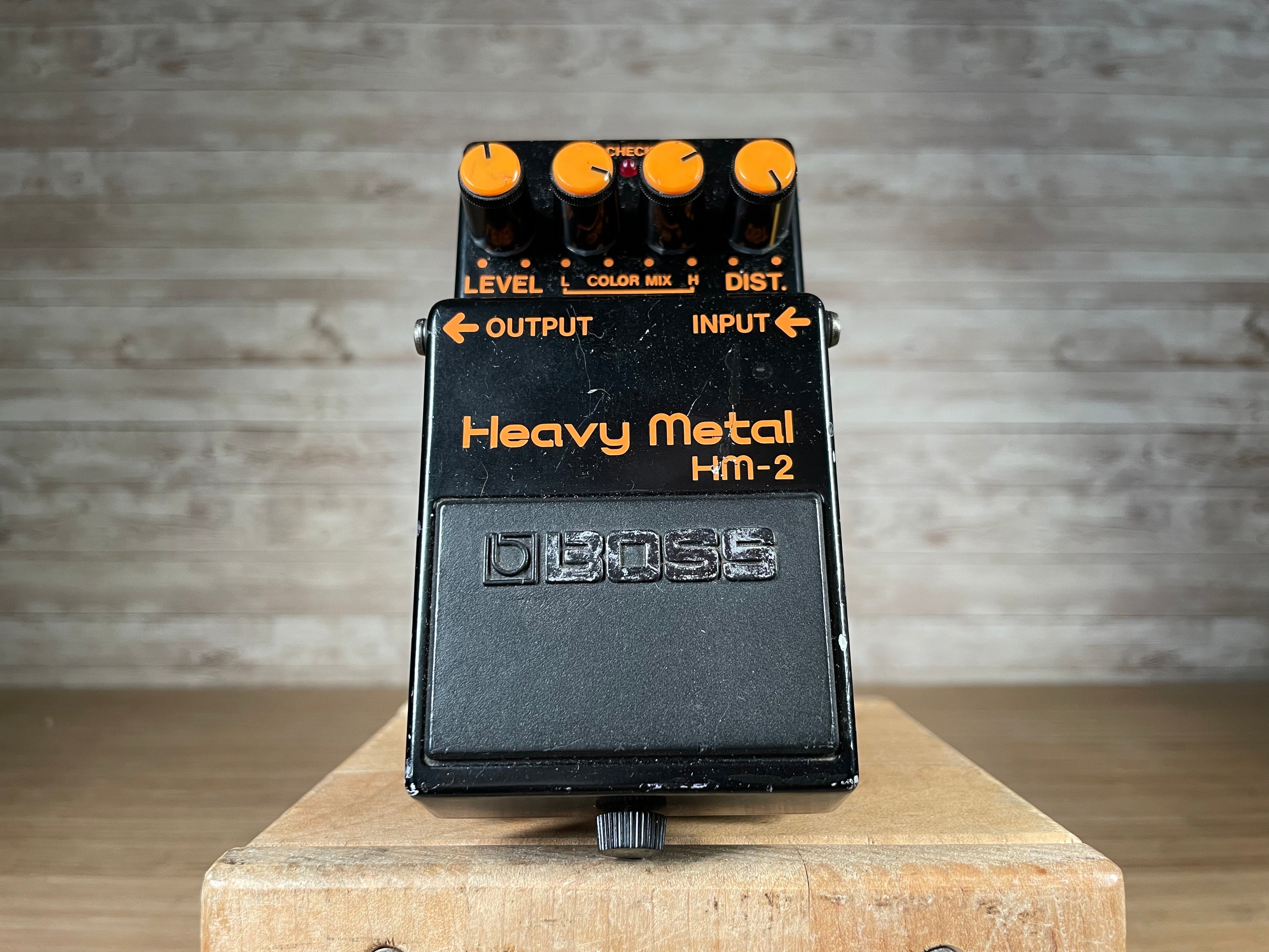 Black guitar effects pedal with orange knobs labeled Heavy Metal HM-2 by Boss shown from front top view.