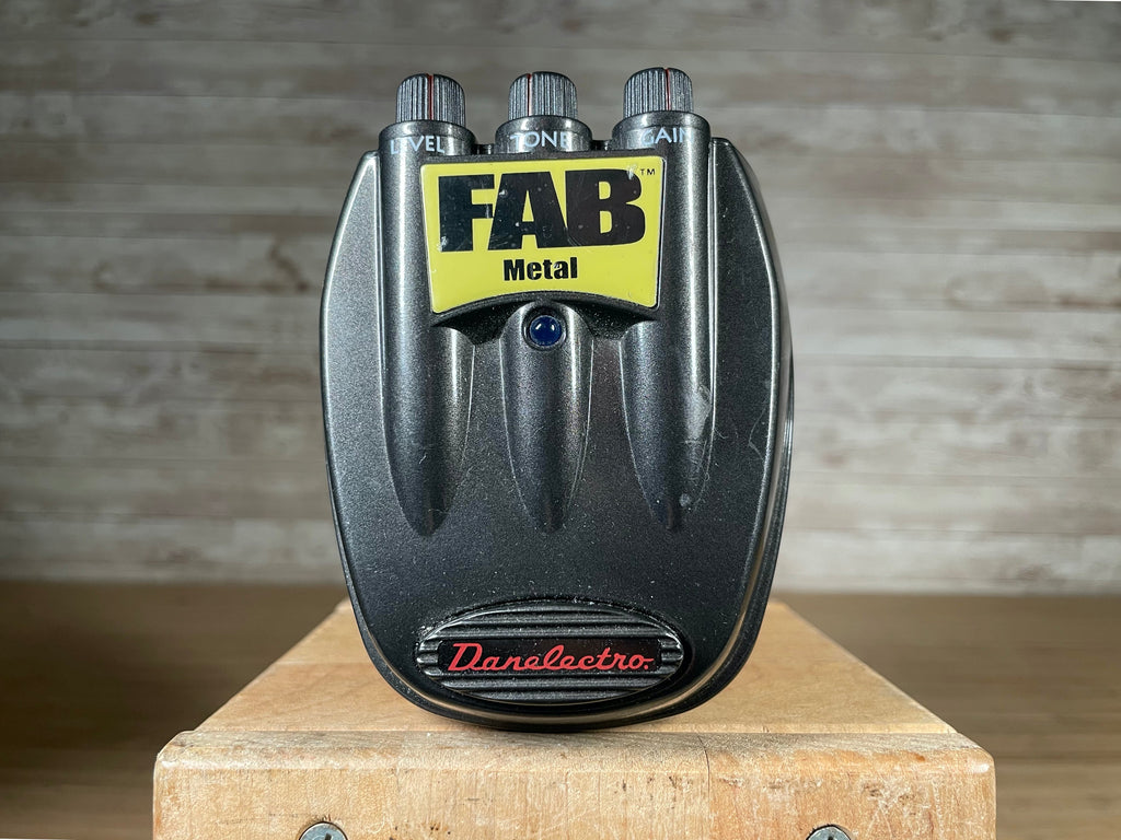 Black Danelectro guitar pedal with three black control knobs labeled Level, Tone, Gain and a yellow label reading FAB Metal.