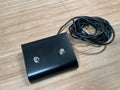 Black two-button footswitch with attached cable on a light wooden surface