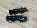 Two black Wilkinson pickups with exposed red and black wires on a wood surface.
