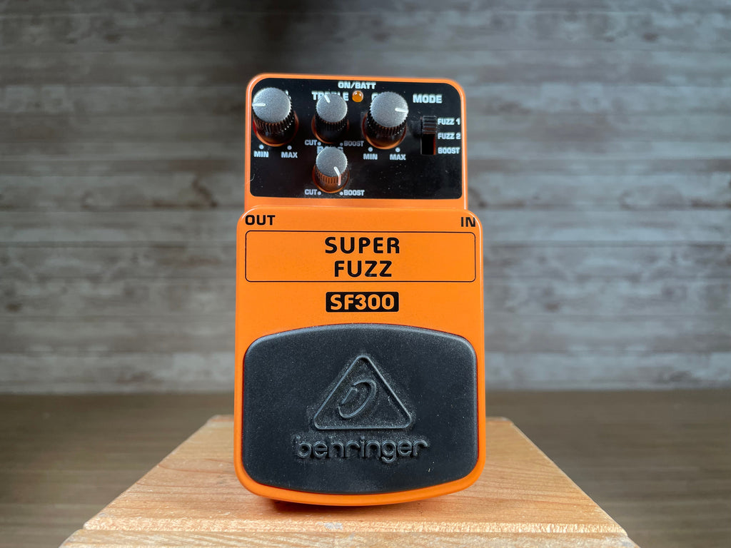 Orange Behringer SF300 Super Fuzz guitar effects pedal with knobs and toggle switch controls.