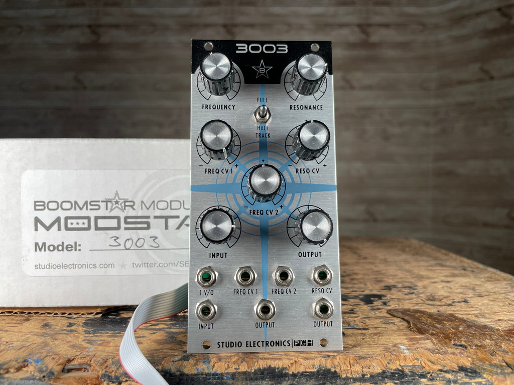 Front view of a Studio Electronics Boomstar 3003 eurorack module with knobs and jacks alongside its original box.