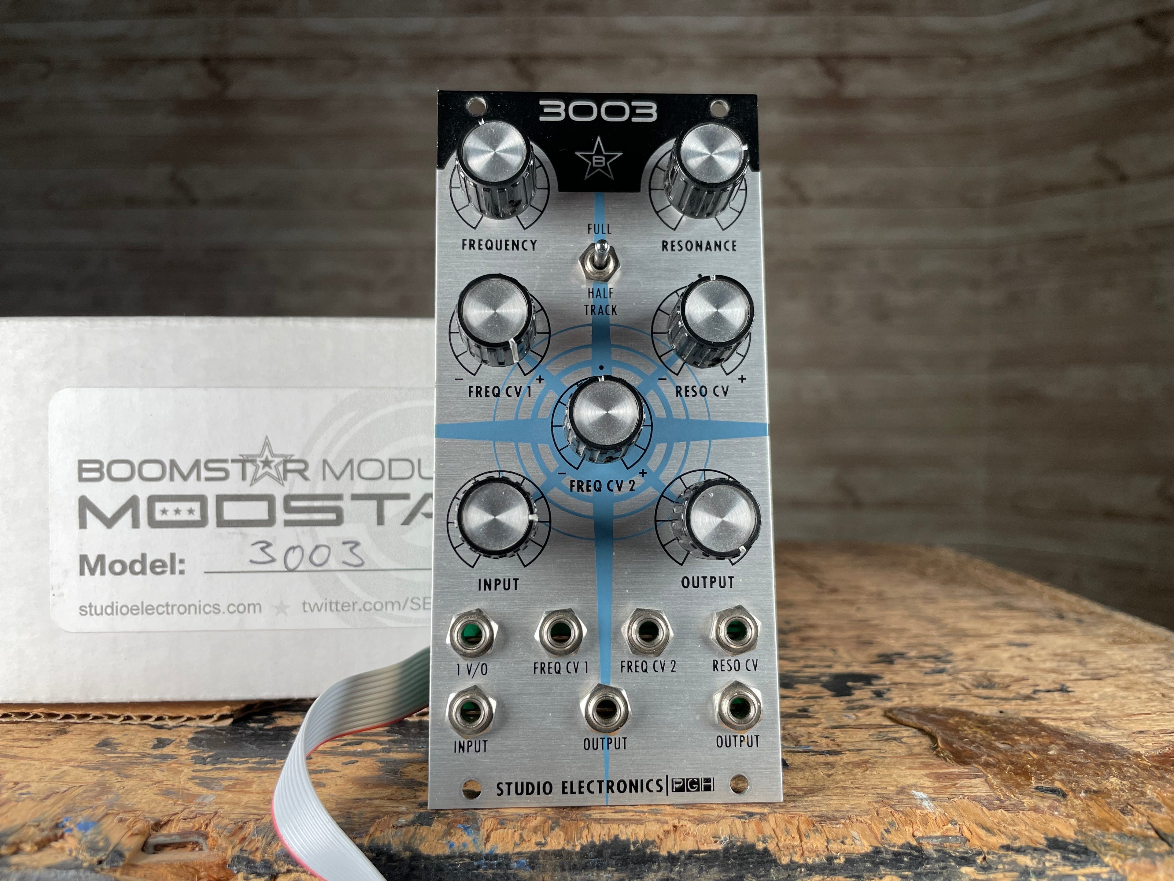 Front view of a Studio Electronics Boomstar 3003 eurorack module with knobs and jacks alongside its original box.