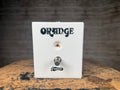 White rectangular metal footswitch pedal with one button labeled switch and Orange logo above it.