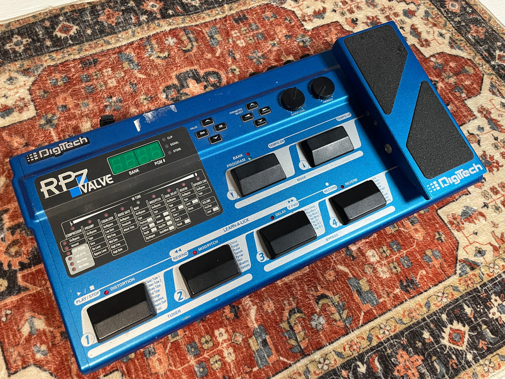 Blue Digitech RP7 Valve multi-effect guitar pedal with knobs, buttons, footswitches, and an expression pedal on a rug.