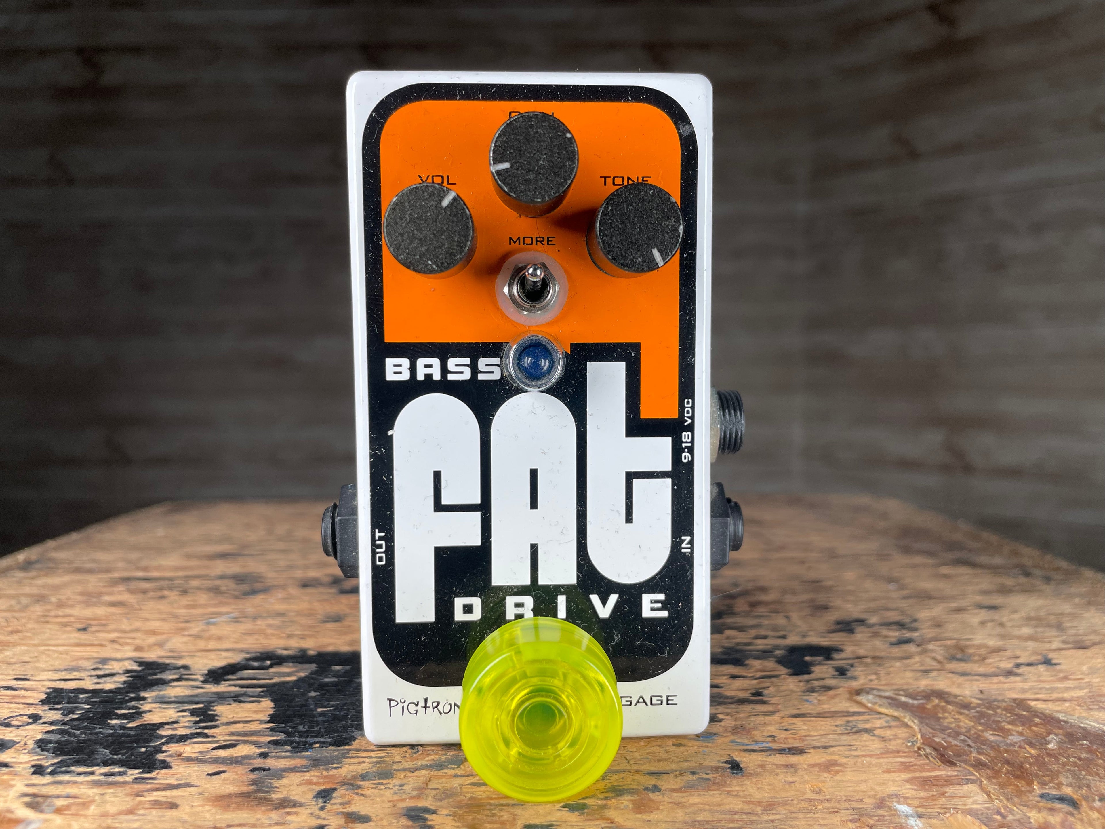 White and orange guitar effects pedal with three knobs, toggle switch, and blue LED on a wooden surface.