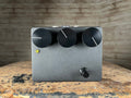 Black rectangular guitar effects pedal with three large knobs, one footswitch, and a yellow LED indicator on front panel.