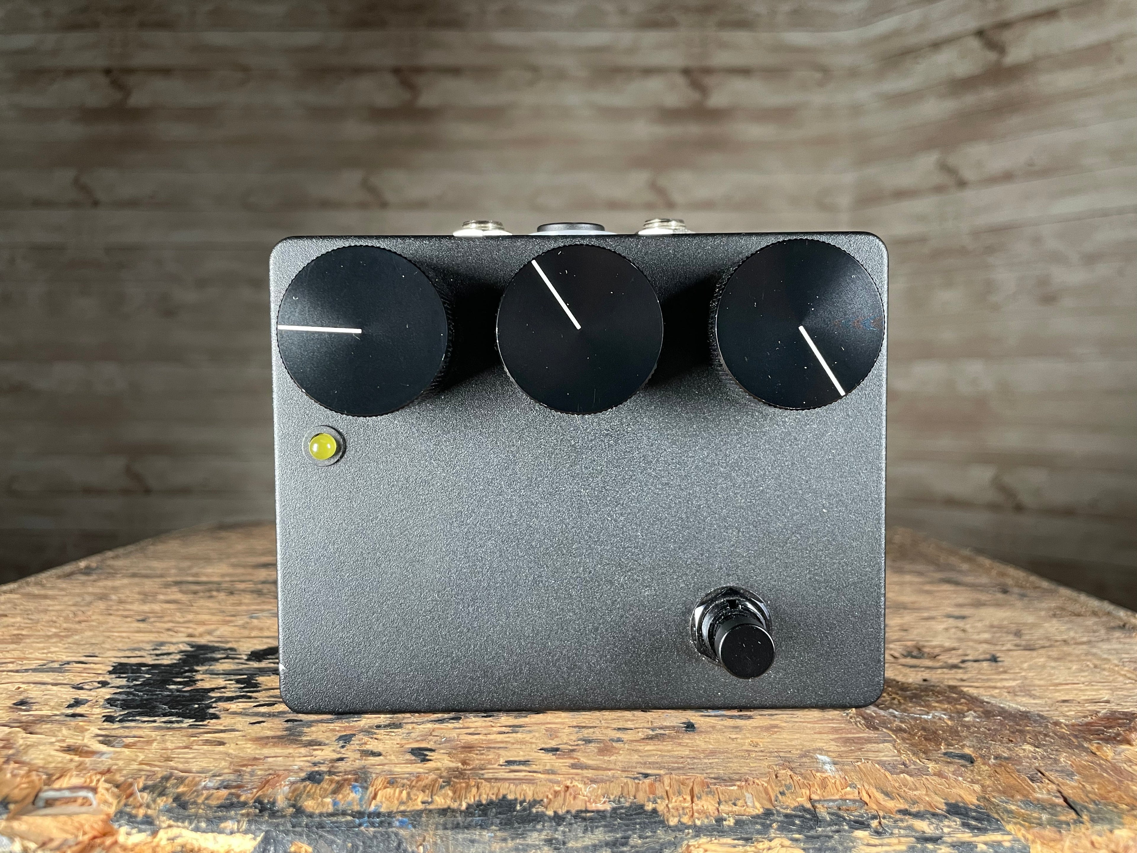Black rectangular guitar effects pedal with three large knobs, one footswitch, and a yellow LED indicator on front panel.