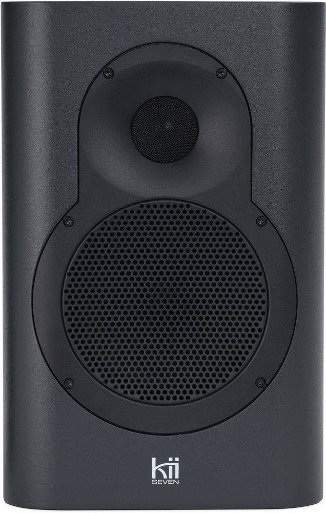 Front view of a dark grey Kii SEVEN speaker with visible tweeter and woofer covered by a metal mesh grille.