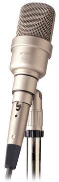 Silver microphone with metal mesh grill labeled M 930 mounted on a metal microphone stand.