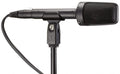 Black shotgun-style microphone mounted on a stand with attached XLR cable and low cut switch.