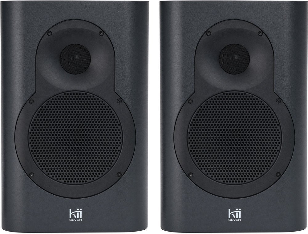 Front view of a pair of dark grey Kii Seven speakers with black speaker grilles and white brand text.