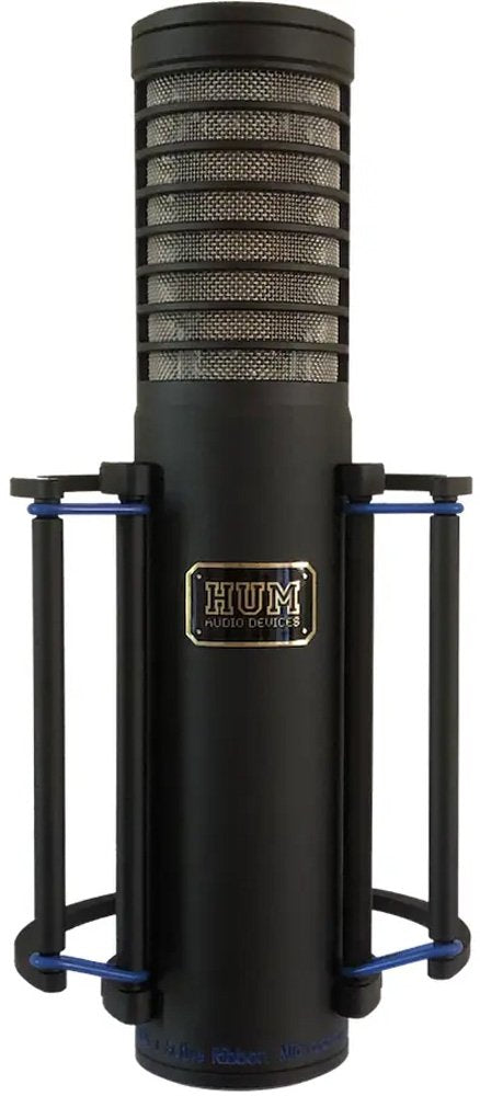 Black cylindrical microphone with protective metal mesh and shock mount, branded HUM Audio Devices.