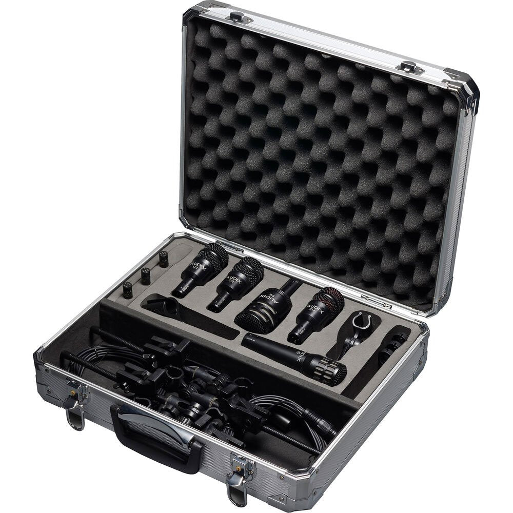 Open hard case containing five black microphones, cables, and microphone clips organized in foam insert.
