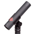Dark gray cylindrical microphone labeled KM 183 mounted on a black adjustable stand mount with Neumann branding.