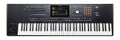 Black keyboard synthesizer with multiple buttons, knobs, sliders, a joystick, and a central display screen.