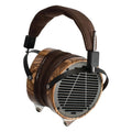 Over-ear headphones with wood ear cups, black metal grille, brown padded headband, and attached audio jack plug.