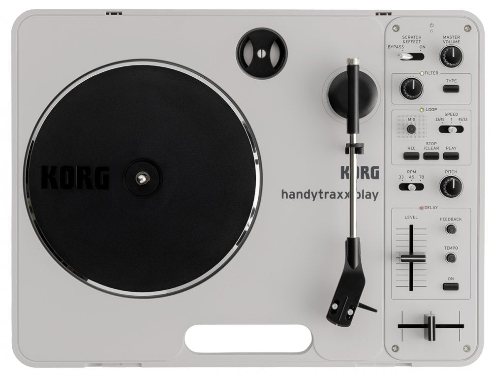 Top view of a Korg handytraxx play DJ turntable with various control knobs, faders, and switches on a gray surface.