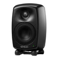 Black Genelec studio monitor with front grille and green indicator light on isolation stand.
