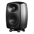 Black studio monitor speaker with a mesh-covered woofer and tweeter on a small isolating stand.