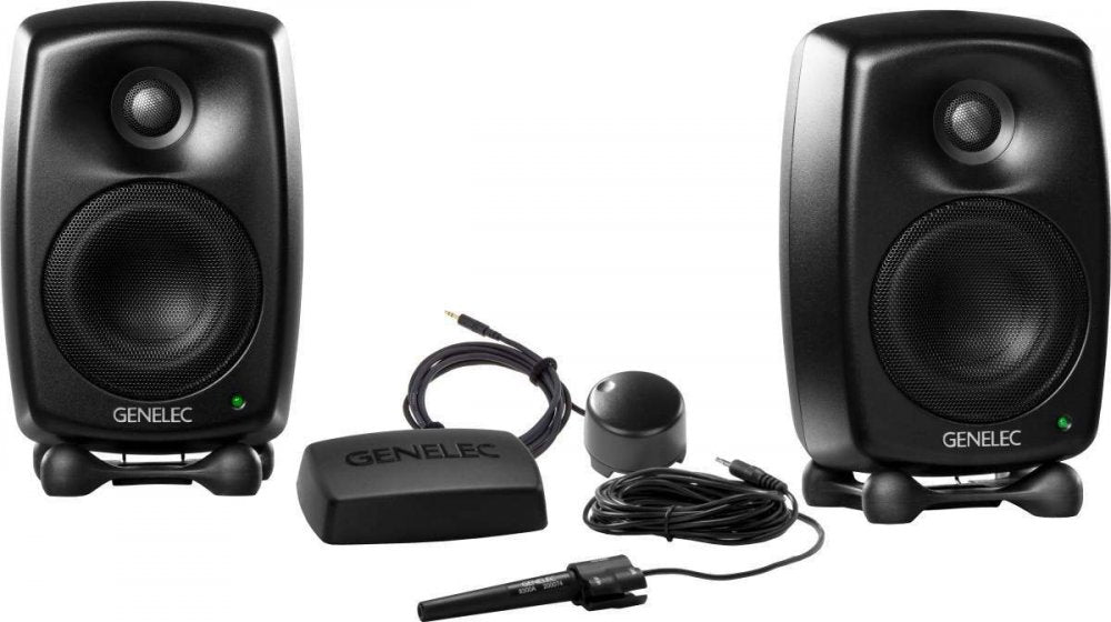 Two black GENELEC speakers with stands, a measurement microphone, cables, and a black device labeled GENELEC.
