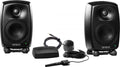 Two black GENELEC speakers with stands, a measurement microphone, cables, and a black device labeled GENELEC.
