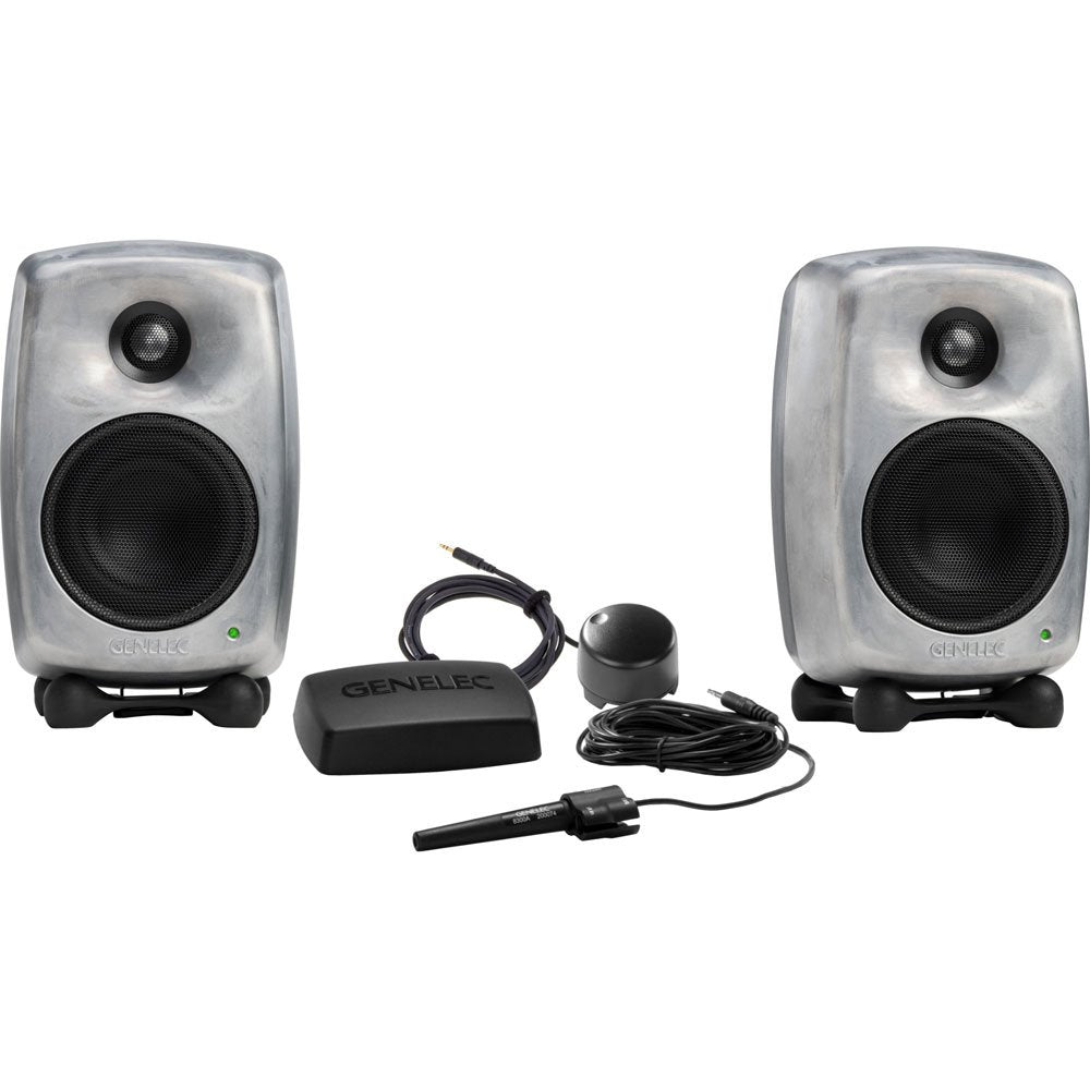 Two gray studio monitor speakers with black grille and green lights, plus three black accessories including a sensor and cable.