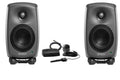 Pair of gray Genelec studio monitors with accessories including a microphone, black rectangular device, and a small round device.