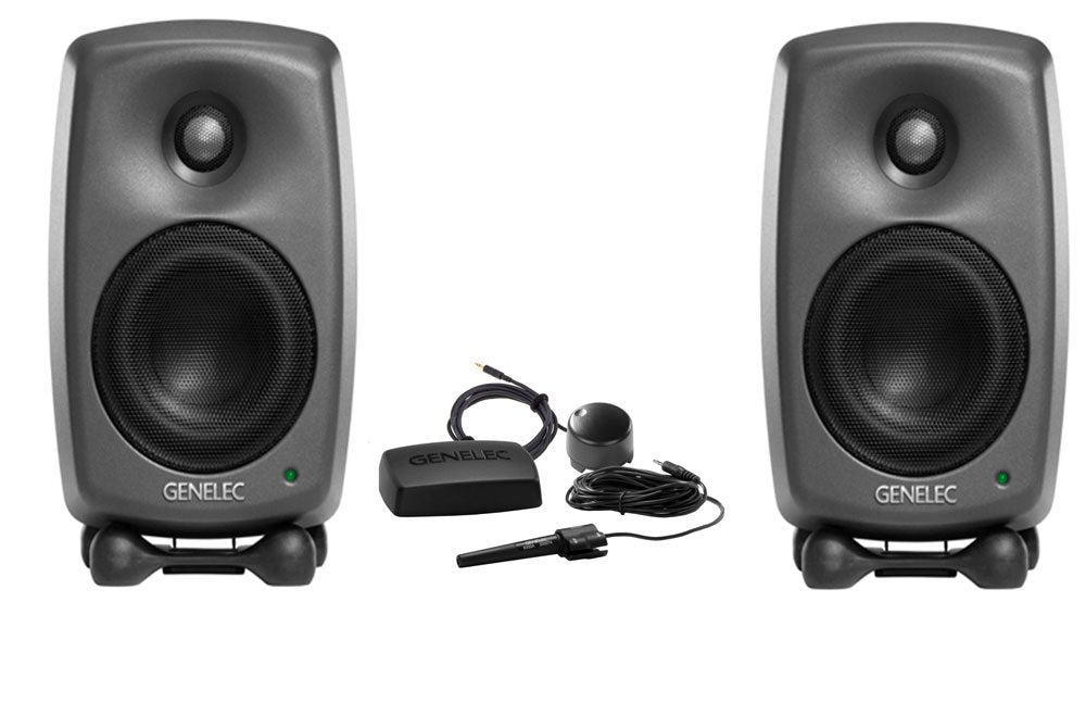 Pair of gray Genelec studio monitors with accessories including a microphone, black rectangular device, and a small round device.