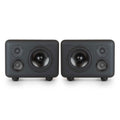 Two black studio monitors each with three speaker drivers and rounded corners on a white background.