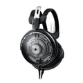 Black open-back headphones with honeycomb grille, dual cables, and adjustable headband shown from angled front view.