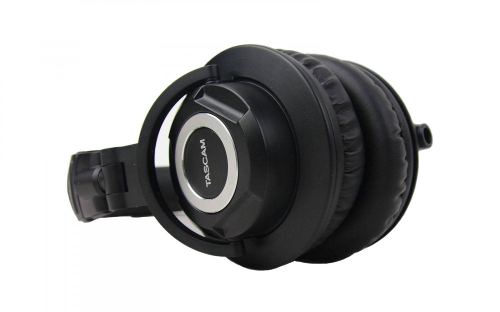 Black over-ear headphones with TASCAM branding on the ear cup and padded ear cushions.