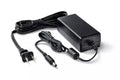 Black power adapter brick with AC power cord and DC barrel connector cable on white background.