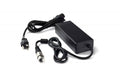 Black rectangular power supply unit with attached cable and separate power cord featuring a 3-pin circular connector and AC plug.