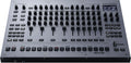 Top view of a Roland TR-1000 rhythm creator drum machine with multiple knobs, faders, buttons, and a small display screen.