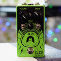 Green guitar effects pedal with three knobs, two toggle switches, one footswitch, and cartoon face artwork.