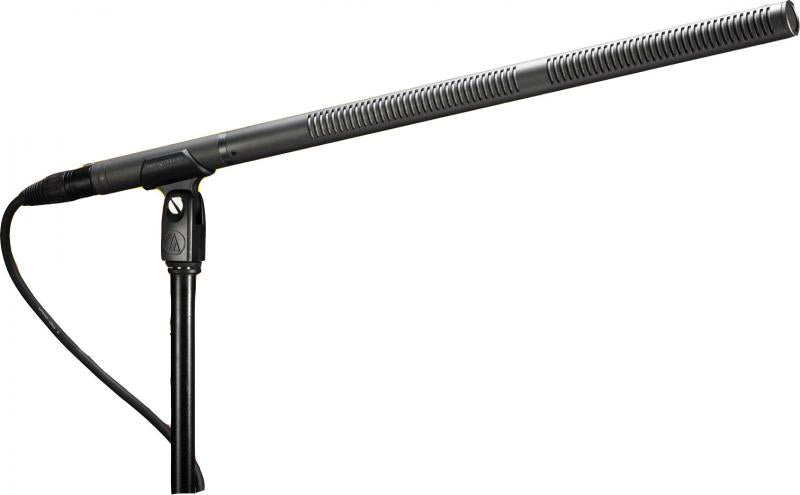Long shotgun-style microphone mounted on a black microphone stand with visible cable and XLR connector.