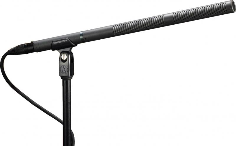 Black shotgun microphone mounted on a stand with attached cable and XLR-type connector.