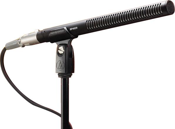 Black shotgun microphone on a stand with a connected cable and mount tightening knob.