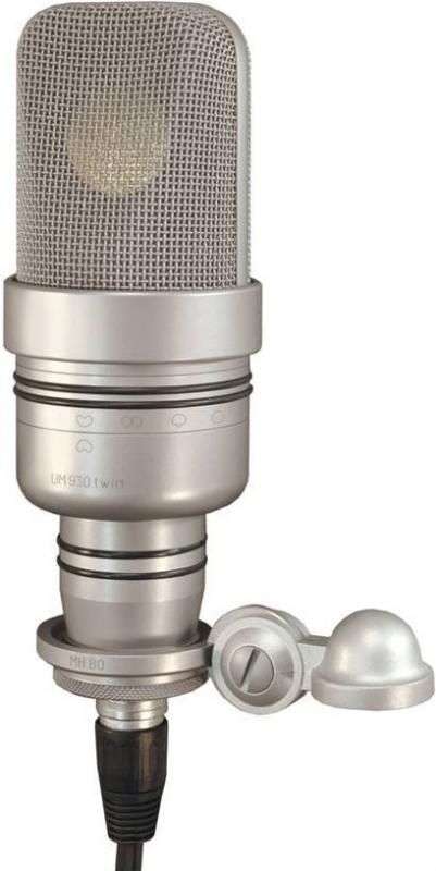 Silver studio microphone with mesh grille, control markings, and attached mounting hardware with cap