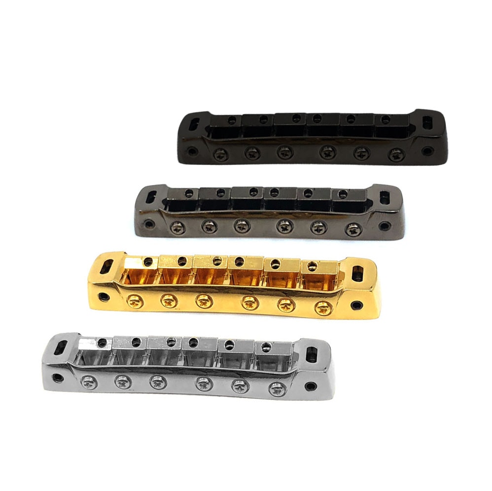 Four Tune-O-Matic style guitar bridges in black, dark gray, gold, and silver finishes arranged on a white background.