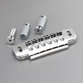 A metallic silver wraparound guitar bridge with two cylindrical posts and one screw on a gray background.