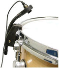 Black microphone mounted on the rim of a snare drum with a visible audio cable attached.