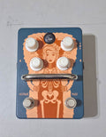 A blue metal Orange Fur Coat guitar effects pedal with four control knobs and two footswitches on a rugged chassis with side-recessed input and output jacks.